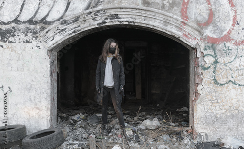 Teenager girl in a black medical mask, on the background of an abandoned post-apocalyptic building. Consequences of COVID-19 Coronavirus protection. After a pandemic