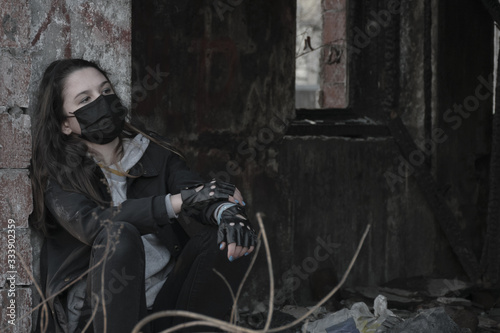 Teenager girl in a black medical mask, on the background of an abandoned building. Consequences of COVID-19 Coronavirus protection. After a pandemic