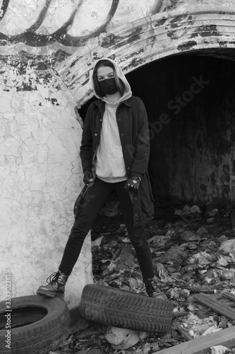 Teenager girl in a black medical mask, on the background of an abandoned post-apocalyptic building. Consequences of COVID-19 Coronavirus protection. After a pandemic