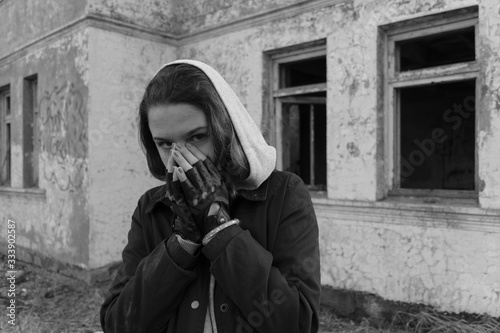 Teenager girl in Black Leather Fingerless Motorcycle Biker Gloves, on the background of an abandoned post apocalyptic building.Consequences of COVID-19 Coronavirus protection. After a pandemic