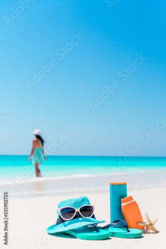 Suncream bottles  goggles  starfish and sunglasses on white sand beach background ocean
