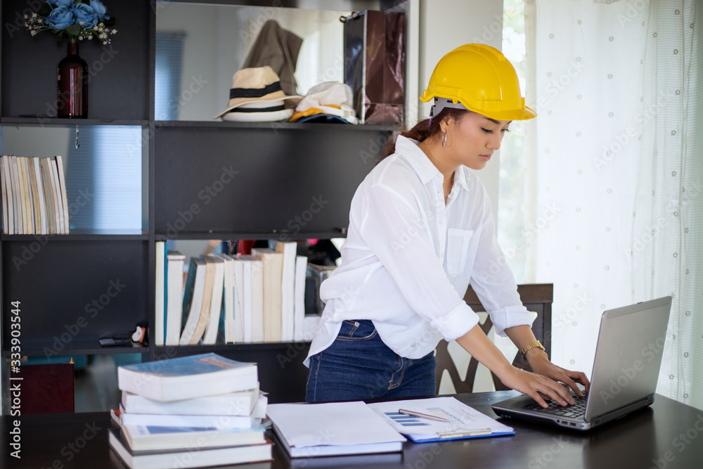 Beautiful Asian engineering women checking document and using notebook working from home for social distance and self responsibility concept Beautiful Asian engineering women checking document and using notebook working from home for social distance and self responsibility concept