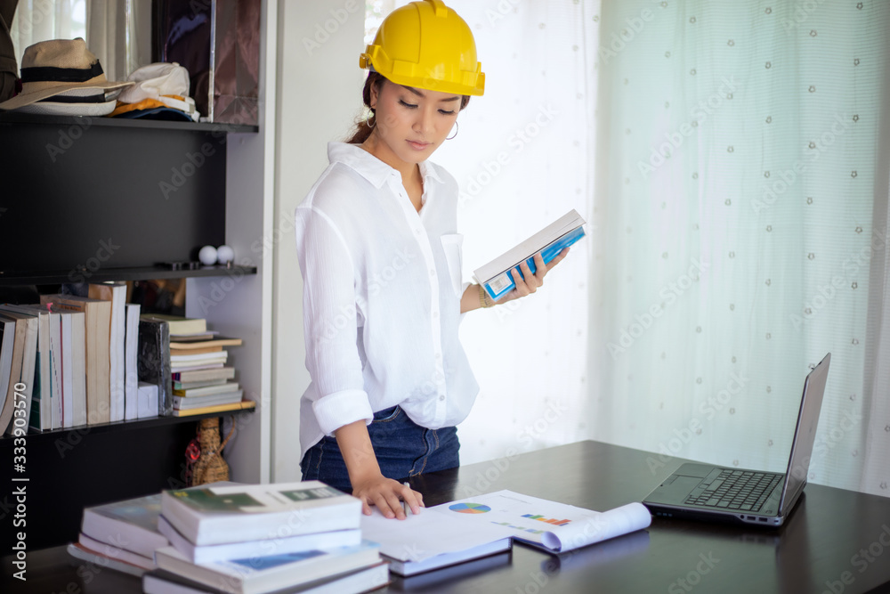 Beautiful Asian engineering women checking document and using notebook working from home for social distance and self responsibility concept Beautiful Asian engineering women checking document and using notebook working from home for social distance and self responsibility concept