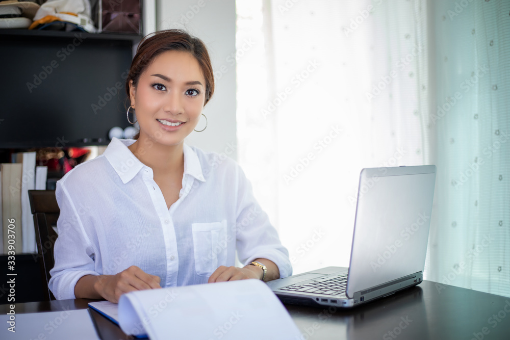 Beautiful Asian business women checking document and using notebook for working at home Beautiful Asian business women checking document and using notebook for working at home