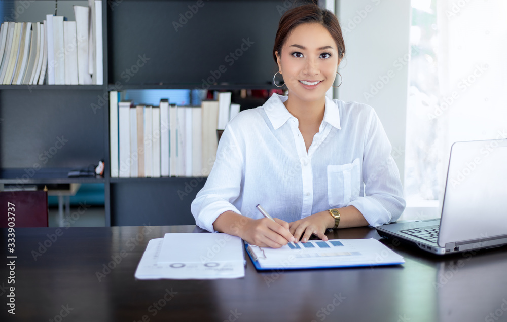 Beautiful Asian business women checking document and using notebook for working at home Beautiful Asian business women checking document and using notebook for working at home