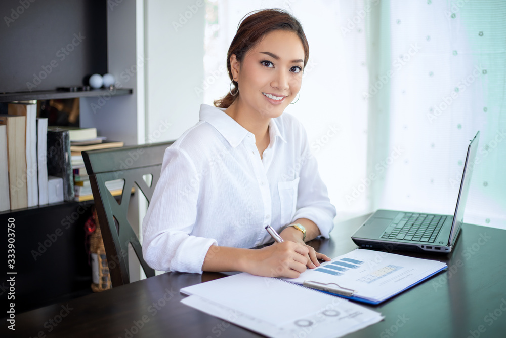 Beautiful Asian business women checking document and using notebook for working at home Beautiful Asian business women checking document and using notebook for working at home