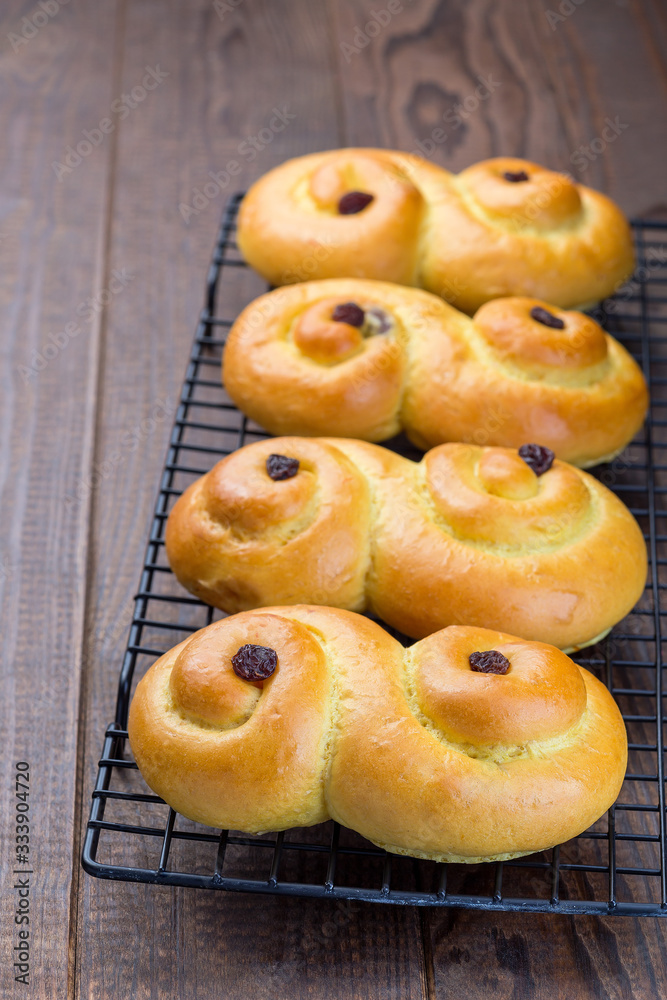 Swedish and scandinavian Christmas saffron buns Lussekatter on cooling tray, brown wooden background, vertical, copy space Swedish and scandinavian Christmas saffron buns Lussekatter on cooling tray, brown wooden background, vertical, copy space