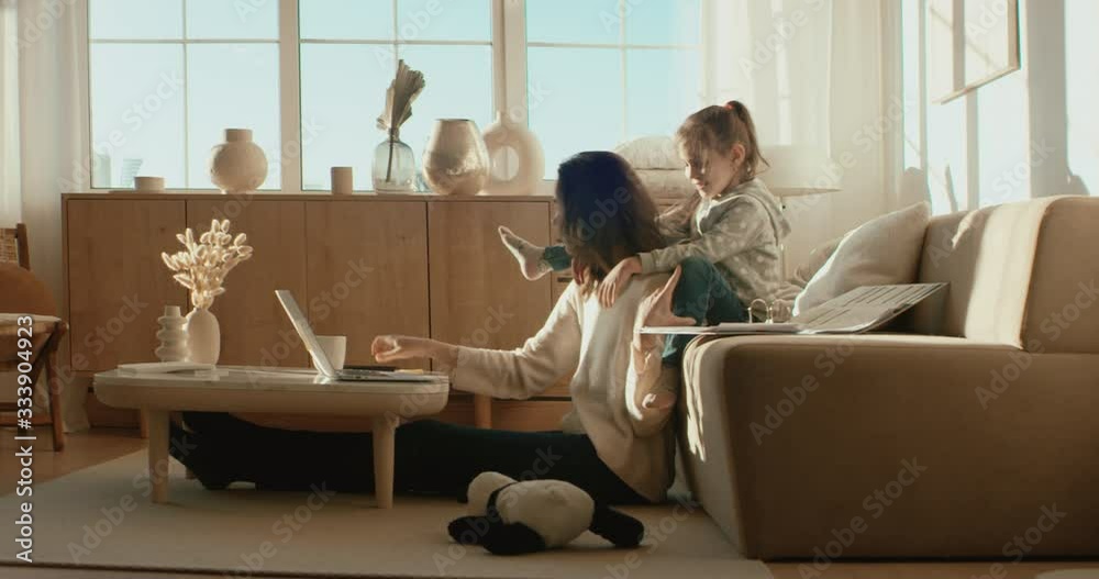 Mother working from home, having a phone call, while her daughter distracts her and drawing attention. Shot on RED Dragon