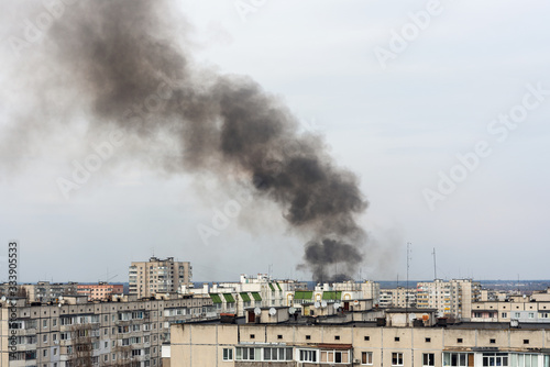 Thick black smoke rises above the city and residential buildings. Fire in the city