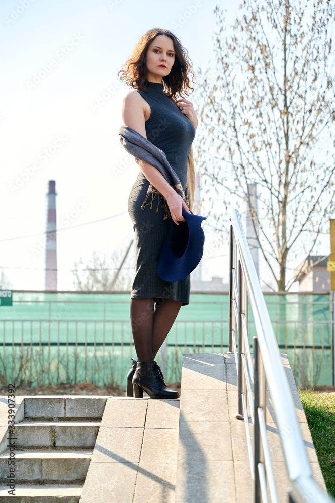 Photo of beautiful slim brunette girl posing outdoors in the spring sun in the city