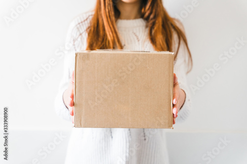 Young woman received the delivery of a cardboard package from a courier - Millennial buys products online - Copy space