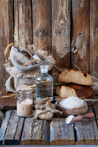 A delicious Danish or Latvian
homemade wholemeal sweet and sour rye bread from sourdough on wooden table in village. Sourdough for rye bread. Ingredients for rye Bread Made Of Sourdough