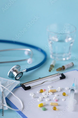 medical concept on a blue background. stethoscope  pills  tablet  notepad  sheet of paper  pen. Medical mask