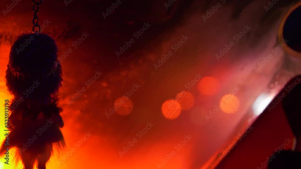 Scary little dolls keychains hanging inside a vehicle with red ambient light creating an evil appeal.