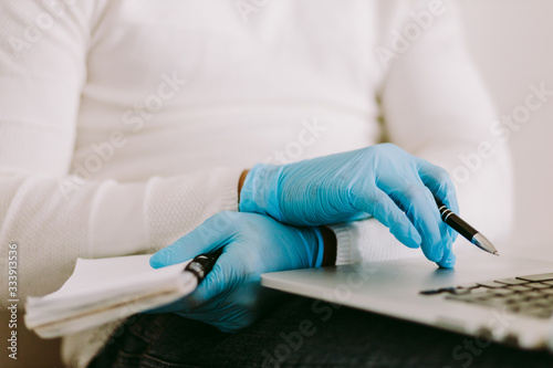 man using laptop and wearing latex gloves at home quarantine