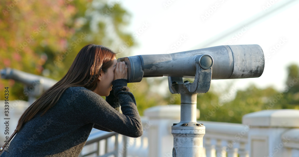 Woman tourist looking though the binocular at outdoor