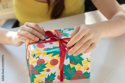 The girl takes a gift from the packaging, untie the ribbon