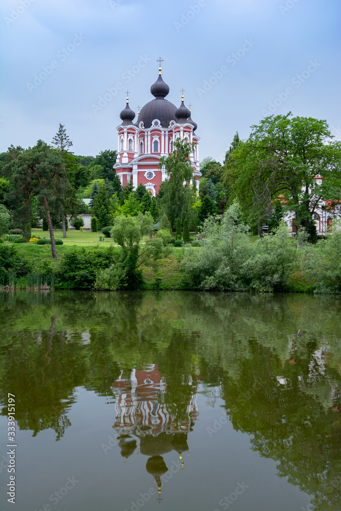 View of the orthodox cathedral in Curchi Monastery reflected in the pond, Moldavia