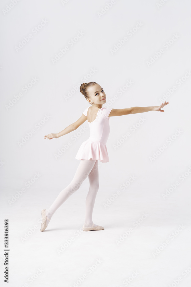 Adorable pre-teen ballerina dancing on white background