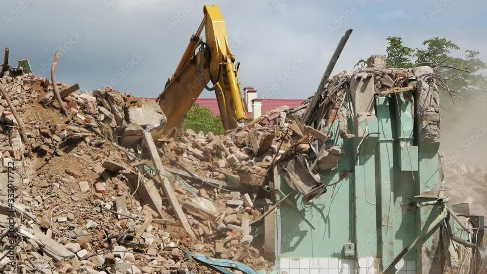 bucket Excavator working to get rid of the rubbish in a demolition site. Demolition of the old industrial building.