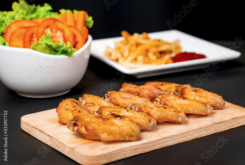 fast food , french fries and fried chicken , with green salad, tomatoes on dark table