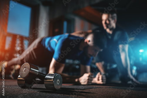 Photo young man has workout with personal trainer in modern gym