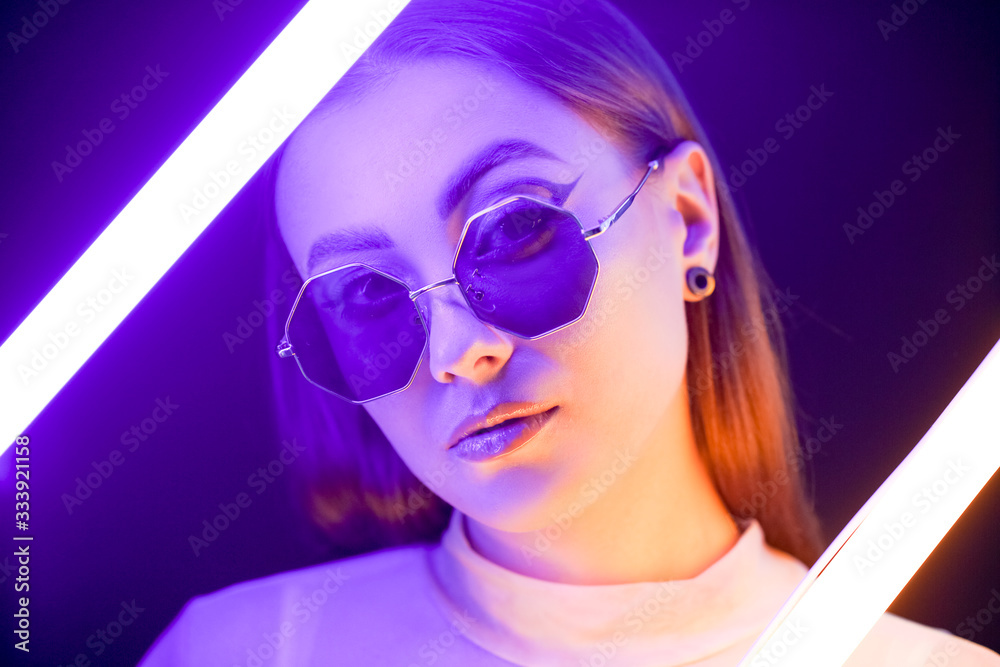 Toned portrait of beautiful woman with neon lamps on dark background