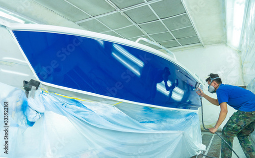 Repairman fixing by painting boat body and painting boat using spray gun