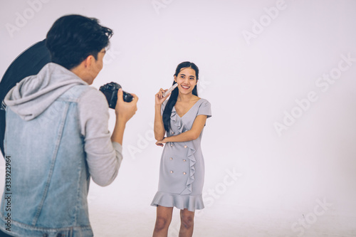 Photographer shooting with Asian model holding cosmetic products in her hand