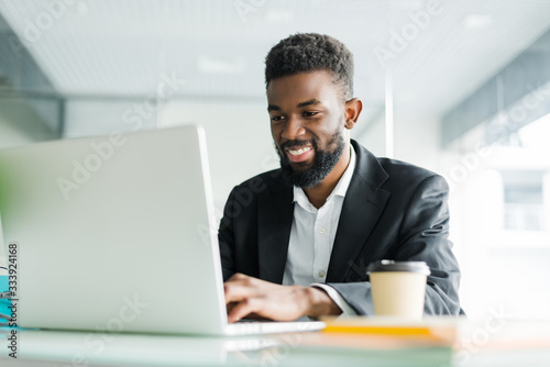 Portrait of young African man typing on laptop in office