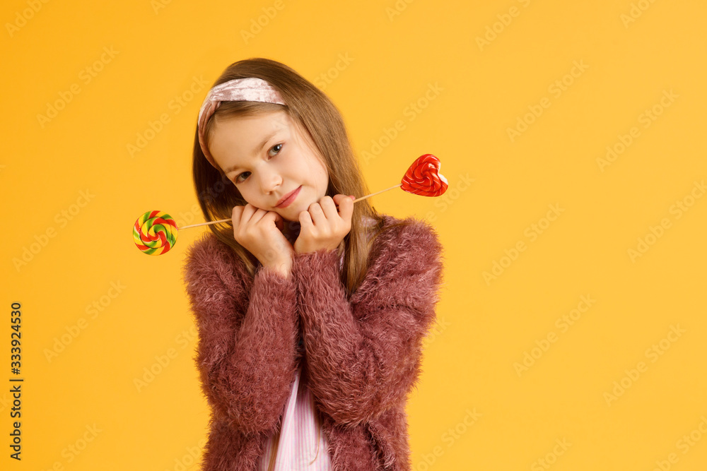 Little girl enjoy lollipops during school break. Happy small schoolchild eat lollipops. Large swirl lollipops on sticks. Little girl enjoy lollipops during school break. Happy small schoolchild eat lollipops. Large swirl lollipops on sticks.