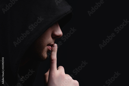 Fotografia A man in a black hood on a black background, studio photography