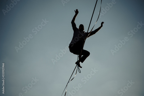 professional man extremely balanced on stretched rope. © fesenko