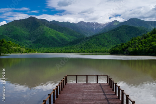 Pier on the lake on a background of mountains and blue sky © VLADISLAV
