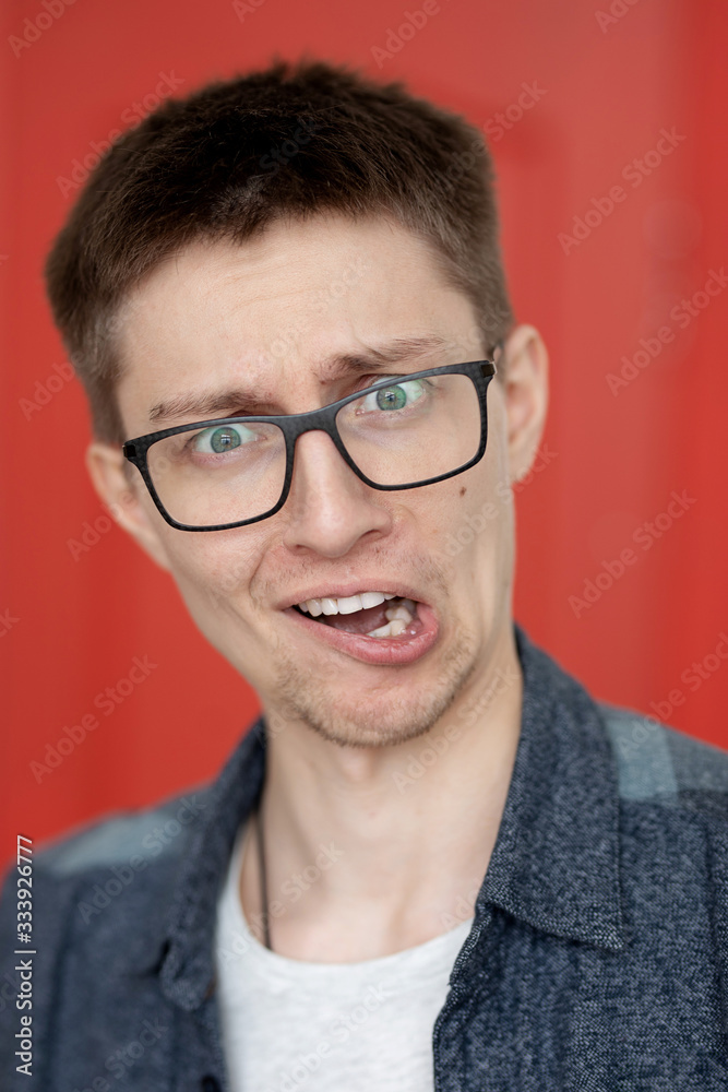 portrait of a cute guy with very bright facial expressions and emotions against a red wall portrait of a cute guy with very bright facial expressions and emotions against a red wall