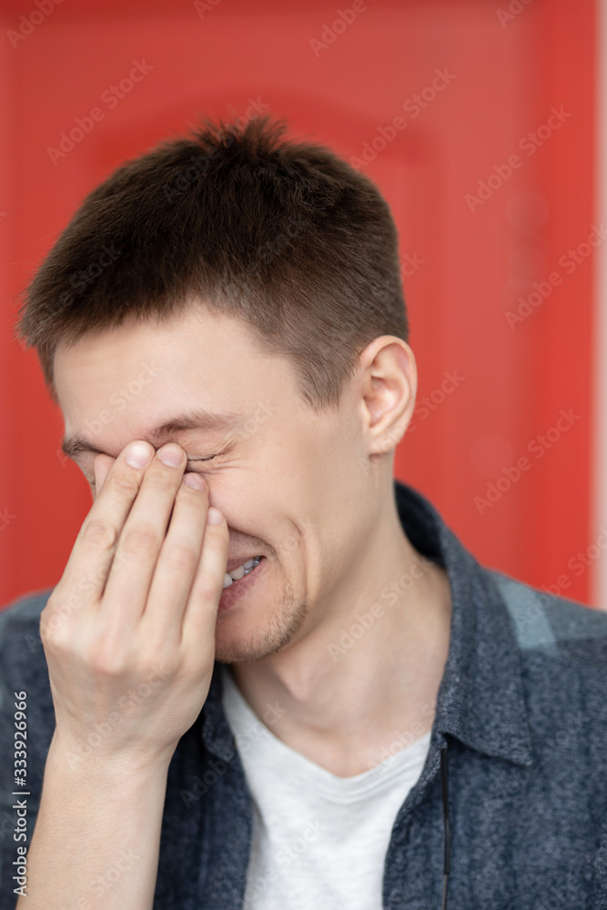 portrait of a cute guy with very bright facial expressions and emotions against a red wall portrait of a cute guy with very bright facial expressions and emotions against a red wall