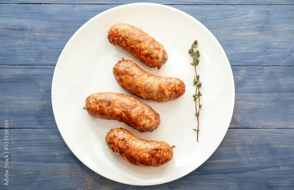 Plate with tasty grilled sausages on color wooden background Plate with tasty grilled sausages on color wooden background