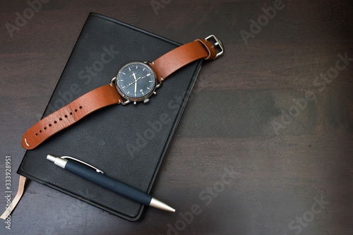 Εκτύπωση καμβά Top view of wristwatch on a notebook isolated on wooden table as background