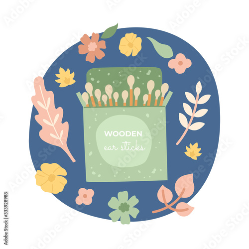 Wooden ear sticks using cotton, in a beautiful green package, on a floral background. Zero waste, organic materials. Go green, less plastic. 