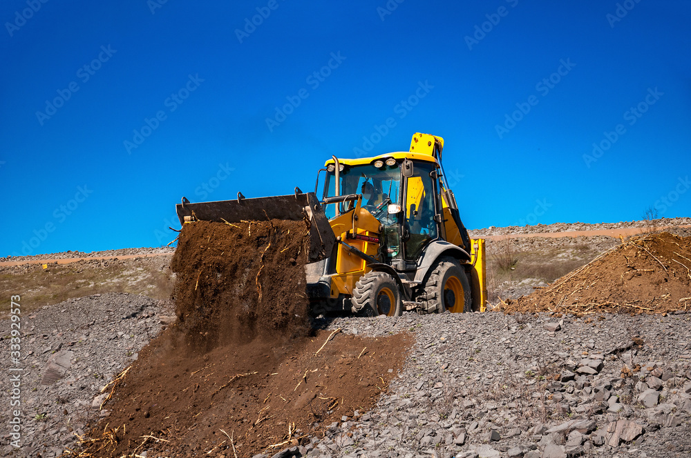 yellow bulldozer dumping rich soil for planting and dust control at waste pile yellow bulldozer dumping rich soil for planting and dust control at waste pile
