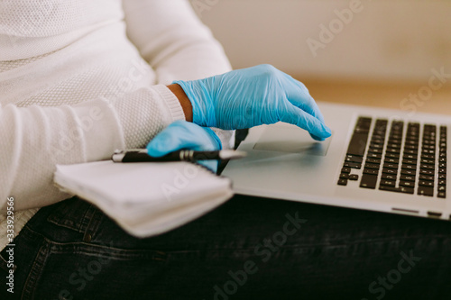 man working on laptop and wearing latex gloves for virus prevention