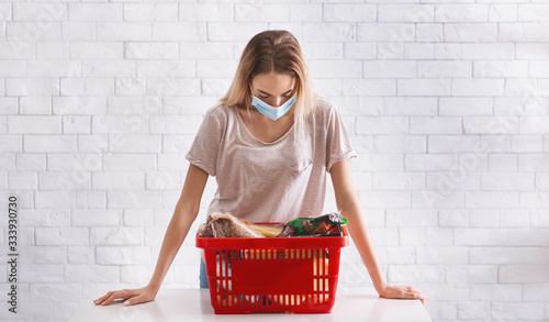 Woman in mask bent over basket of products