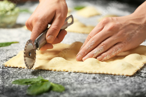 Woman preparing tasty ravioli on table