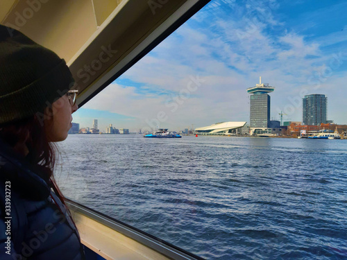 Photography girl looks at the panorama of the city of Amsterdam on a ship on the Dutch canal