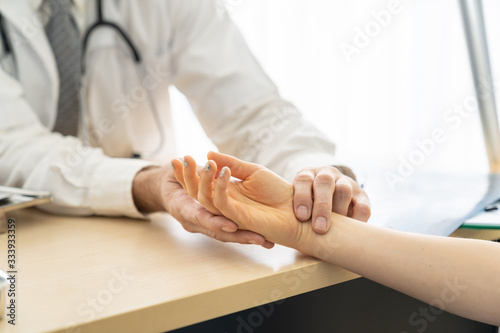 Senior man doctor examining on hand woman patient pulse with his hands. Healthcare and medical concept.