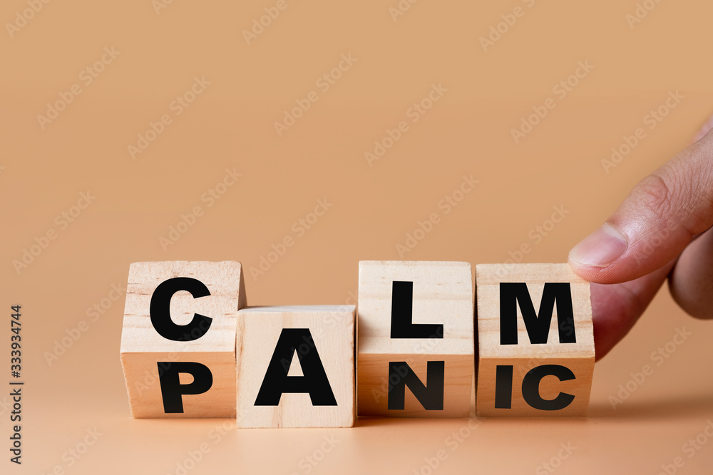 Hand flipping wooden cubes for change wording" Panic "  to " Calm".  Mindset is important for human development. - obrazy, fototapety, plakaty 