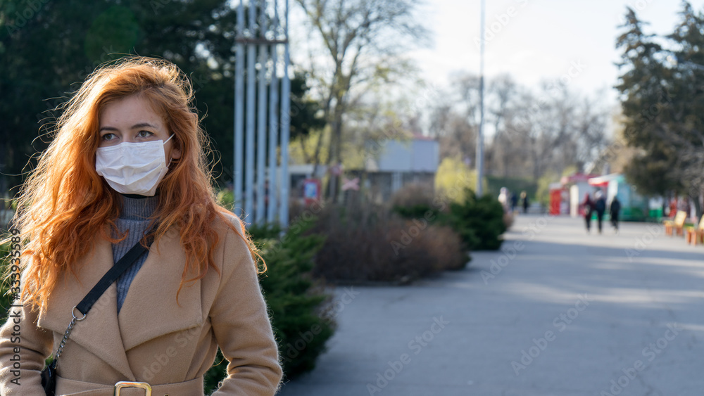 Beautiful red haired girl wearing surgery mask walking on empty streets due to epidemic in city. Women protect herself walking outdoor caused by epidemic in city.Virus protection. Beautiful red haired girl wearing surgery mask walking on empty streets due to epidemic in city. Women protect herself walking outdoor caused by epidemic in city.Virus protection.