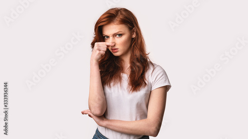 Obraz na plátne Girl Pinching Nose Feeling Stinky Smell Standing On White Background
