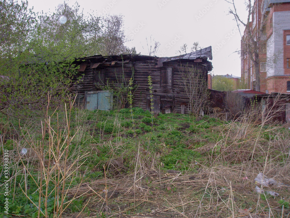 An old crumbling abandoned wooden two story house with a sunken roof and a grassy lawn An old crumbling abandoned wooden two story house with a sunken roof and a grassy lawn