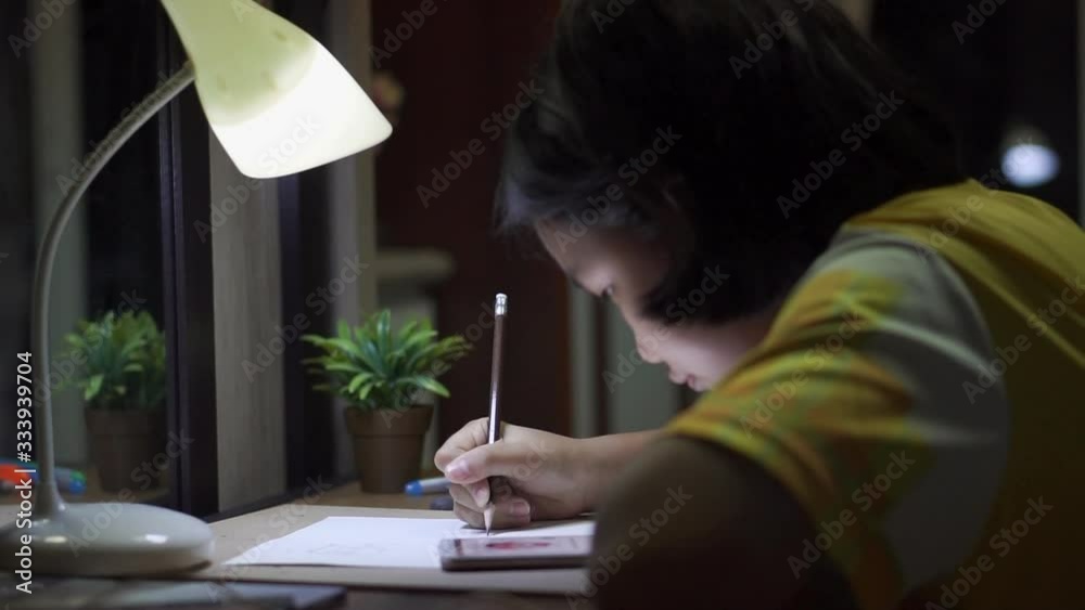 Asian children writting  and doing homework at home.Elementary happy Kid learning and reading book for study to the exam.Education concept.